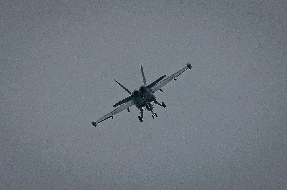 A military jet aircraft is flying in the sky with its landing gear extended.