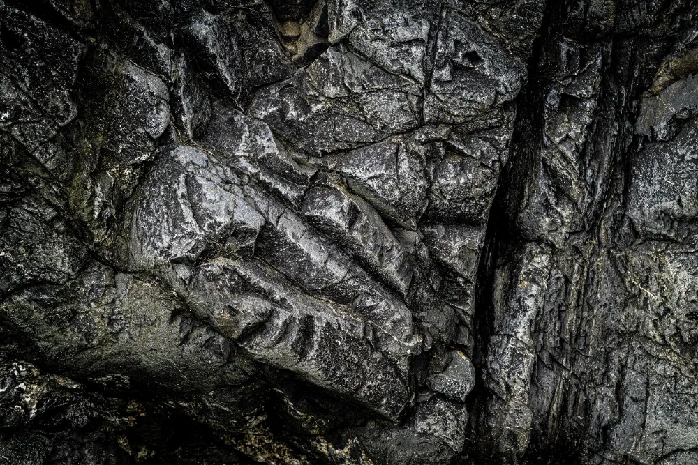 Dark, textured rock formations with distinct, sharp grooves and crevices create a rugged surface.