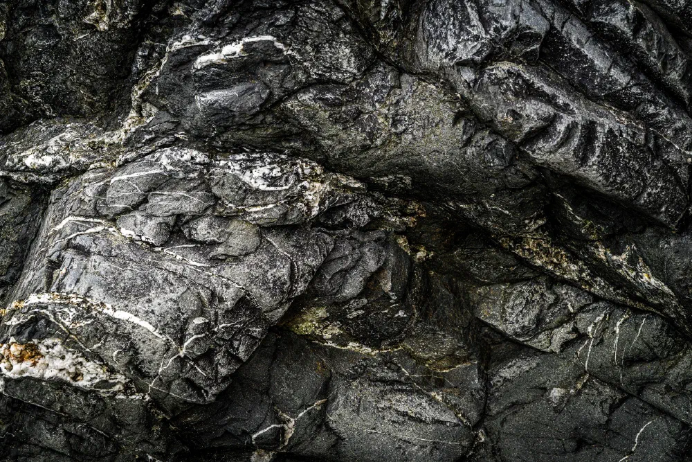 Dark, textured volcanic rock formations with visible cracks and layers dominate the scene.