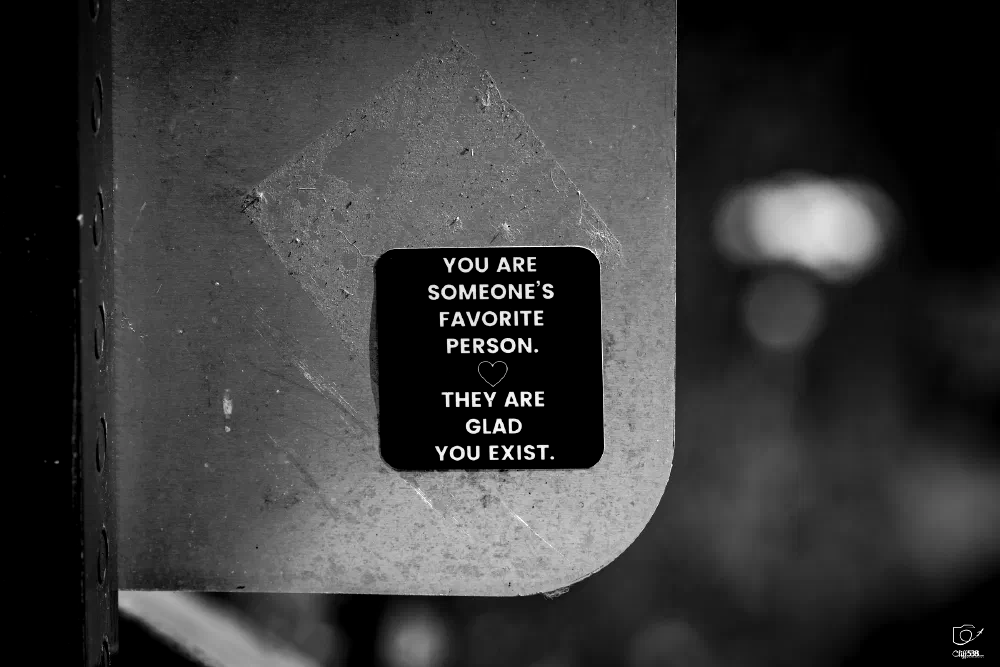 A small black sign with white text and a heart symbol displays a positive and affirming message about being someone's favorite person and being appreciated.