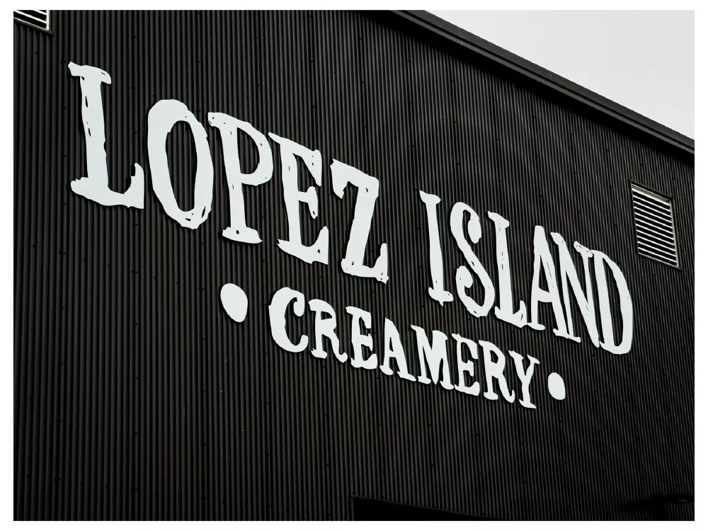 A black corrugated wall features large white letters spelling out Lopez Island Creamery.