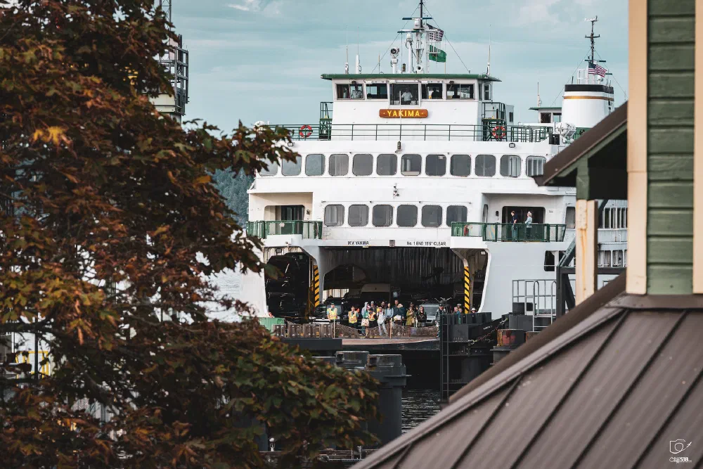 A large ferry named Yakima is docked at a pier with people gathered near its entrance.