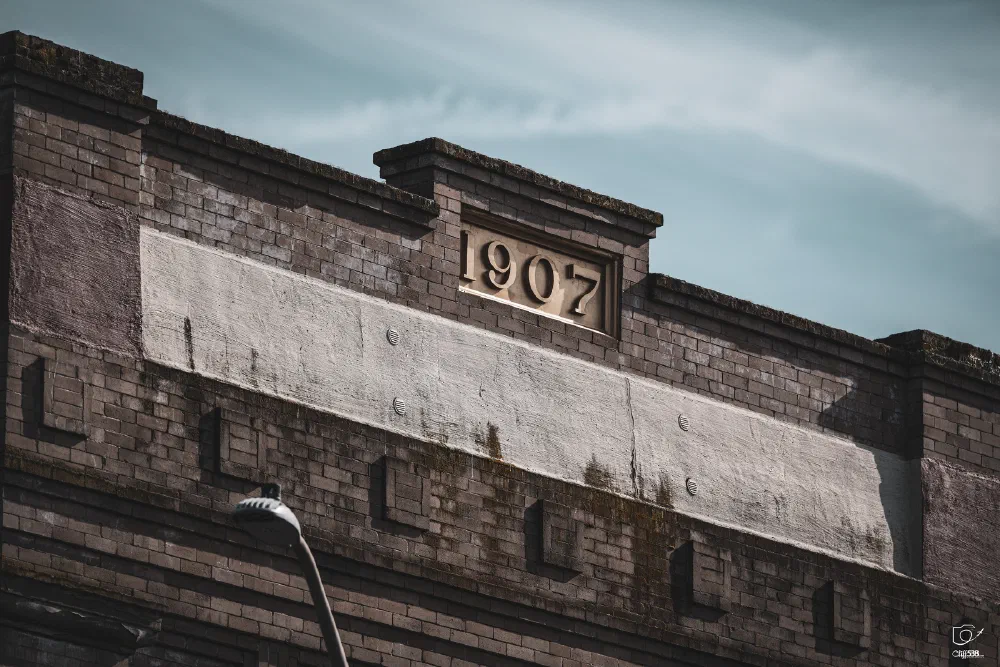 A brick building facade features the year 1907 prominently displayed at the top.