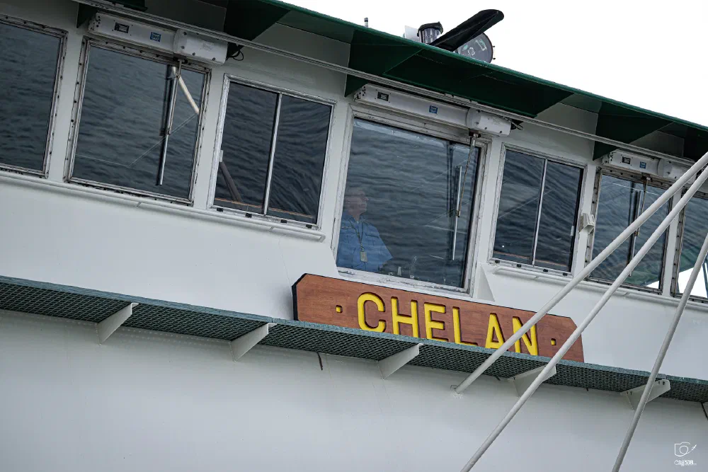 A person is visible inside the cabin of a boat named CHELAN.