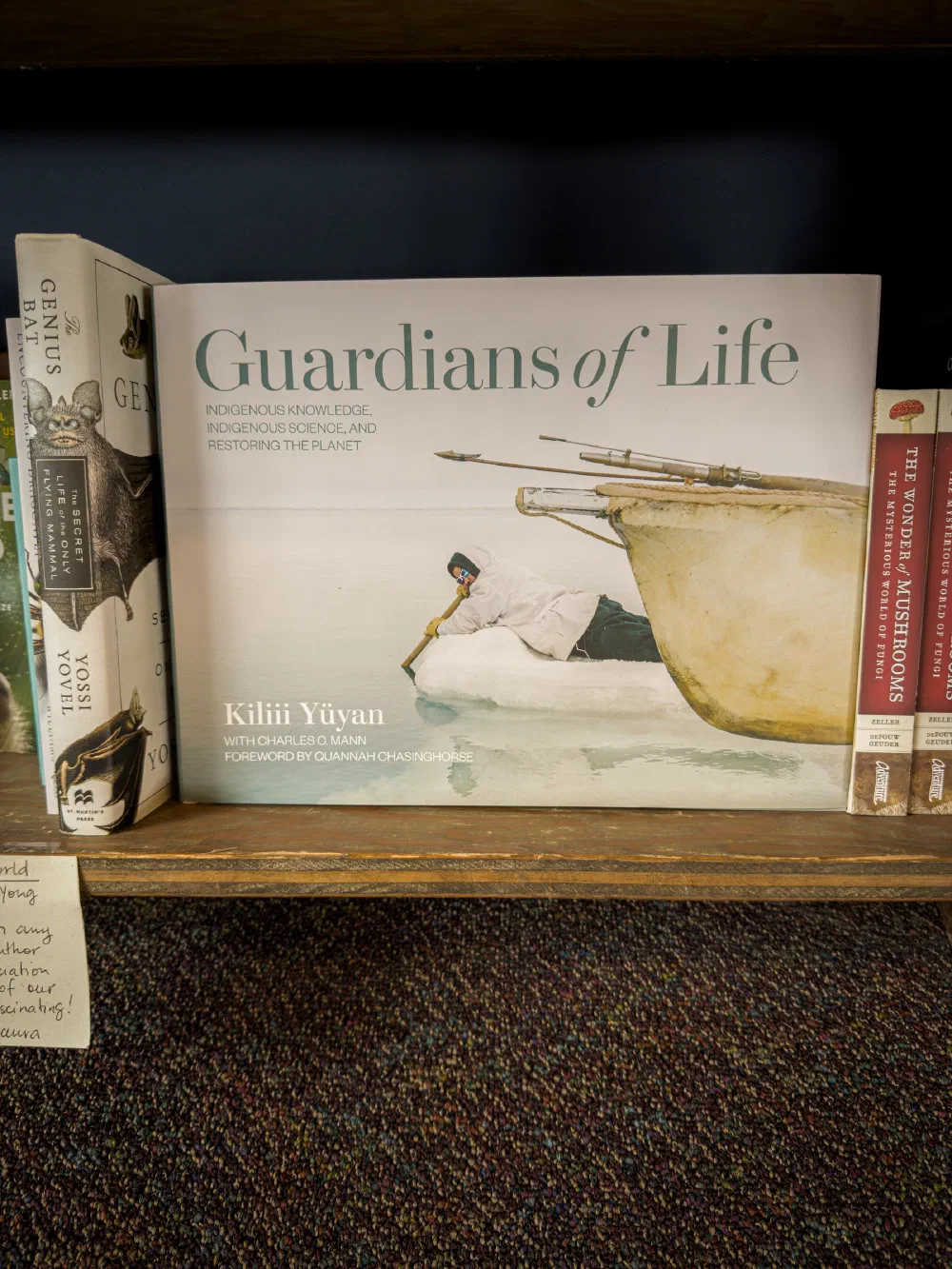 A book titled Guardians of Life by Kilii Yuyan, focusing on Indigenous knowledge, science, and environmental restoration, is displayed on a shelf alongside other books.