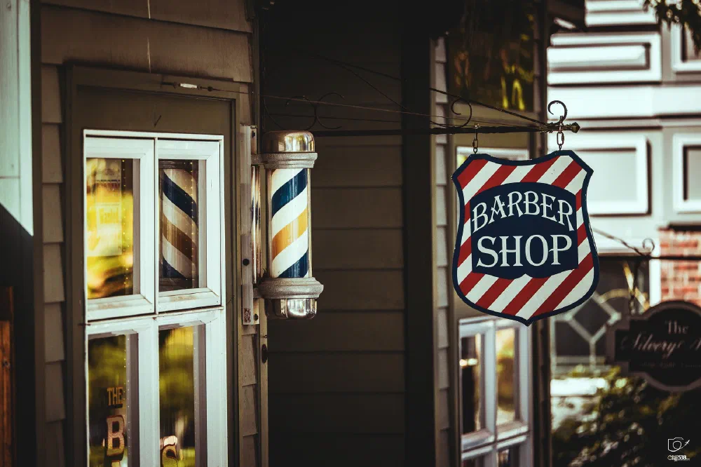 A vintage-style barber shop sign and barber pole are mounted outside a building.
