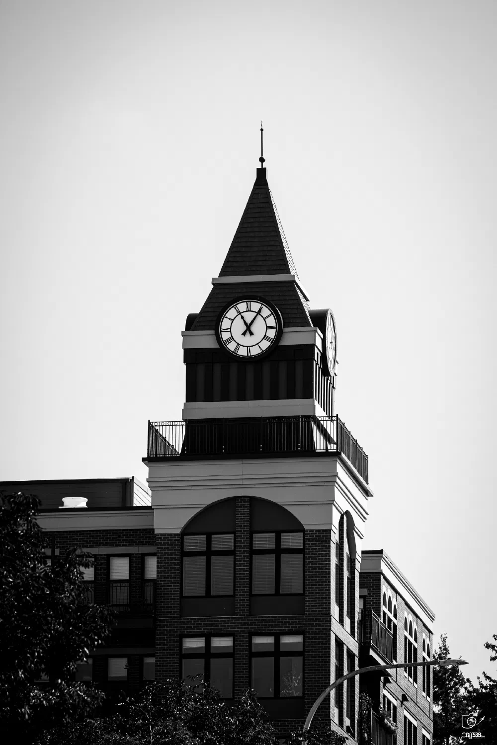 A tall clock tower with a pointed roof stands atop a multi-story brick building, showing the time as 11:00.