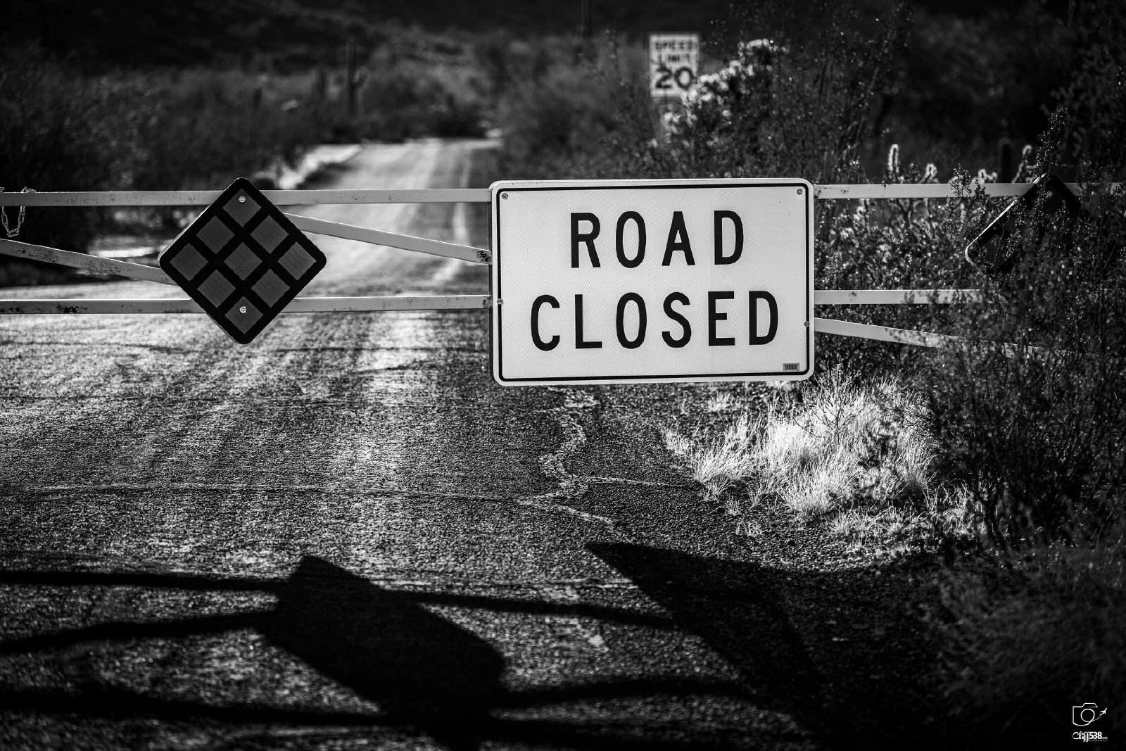 A road is blocked by a gate featuring a ROAD CLOSED sign, indicating that passage is not allowed.